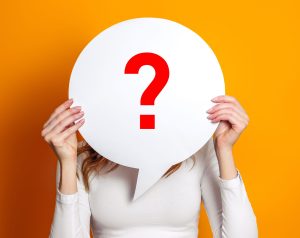 girl wearing white t-shirt holding paper card bubble with question mark isolated over orange background